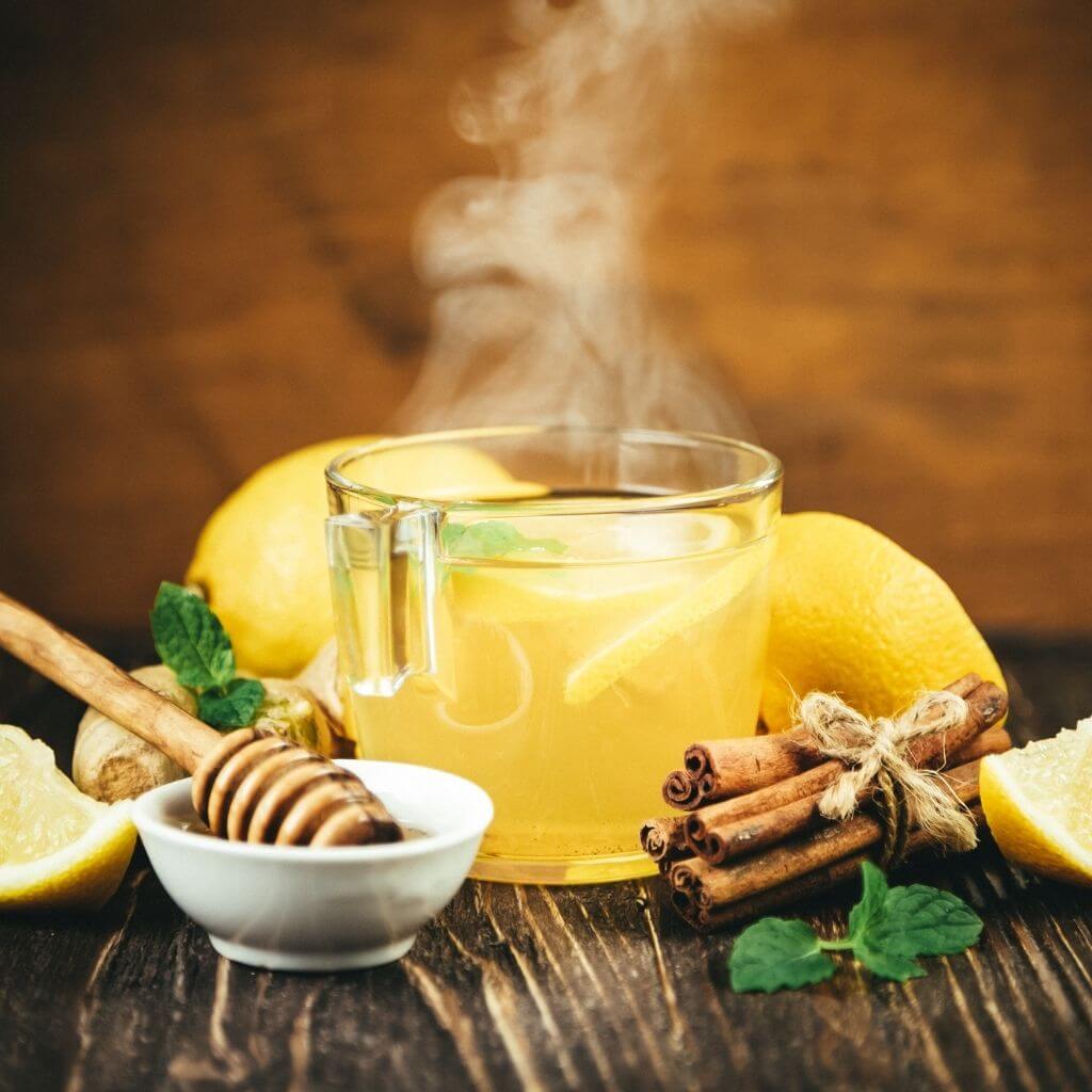 Steaming cup of Honey Irish Breakfast Tea with a drizzle of honey and a saucer with a tea bag.