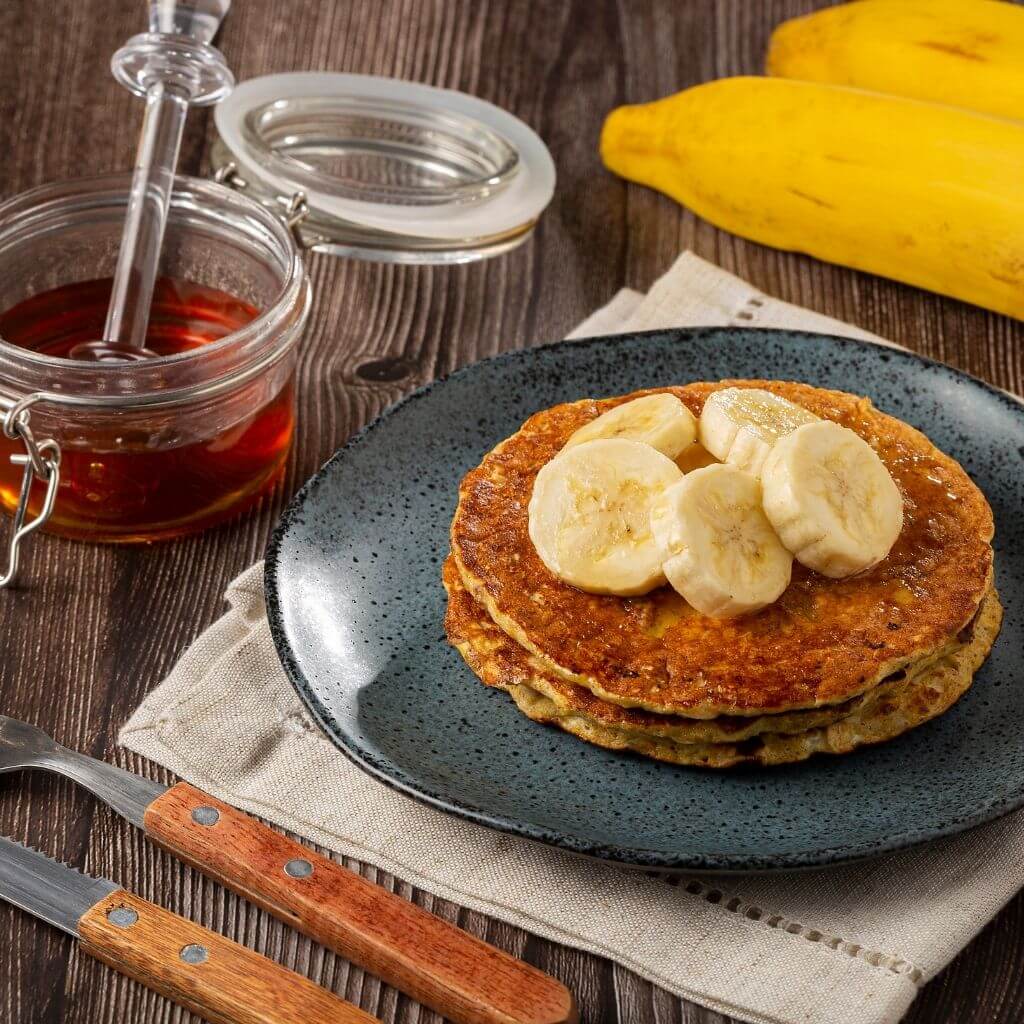 Stack of Honey and Oat Pancakes topped with fresh berries and a drizzle of honey.